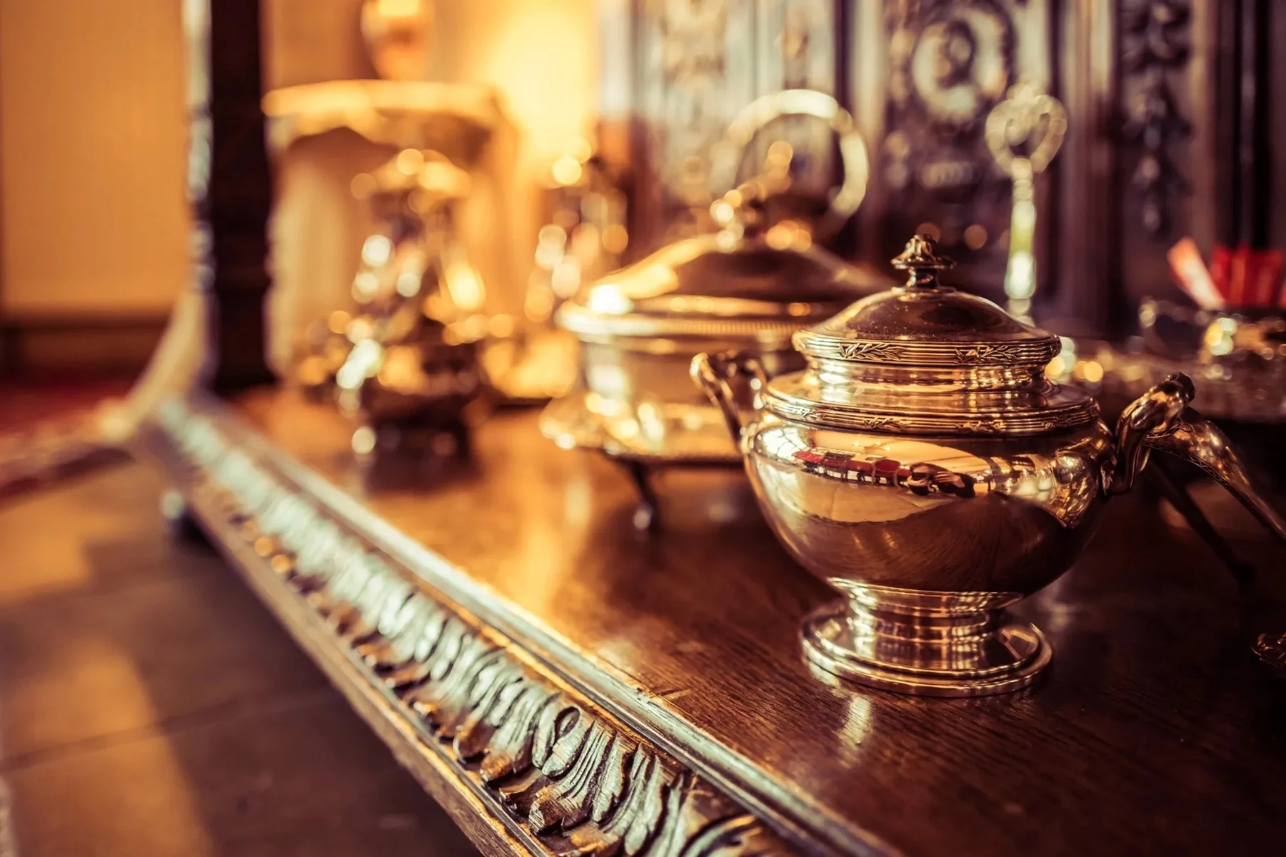 Argenterie ancienne : sucrier et légumier en argent posés sur un buffet en chêne